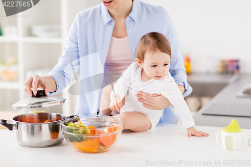 Image of happy mother and baby cooking vegetables at home