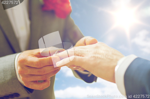 Image of close up of male gay couple hands and wedding ring