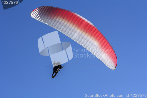 Image of Paraglider flying in the blue sky as background