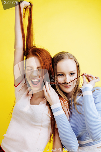 Image of lifestyle people concept: two pretty young school teenage girls having fun happy smiling on yellow background 