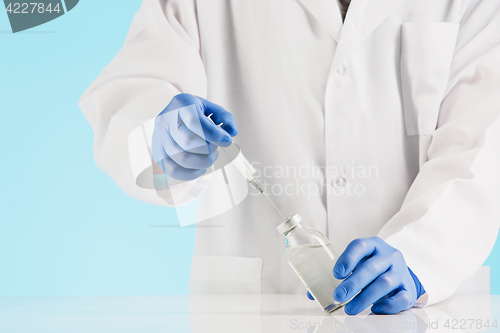 Image of Hand in a blue glove holding syringe on blue