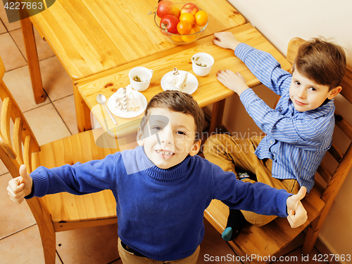 Image of little cute boys eating dessert on wooden kitchen. home interior. smiling adorable friendship together forever friends, lifestyle people concept