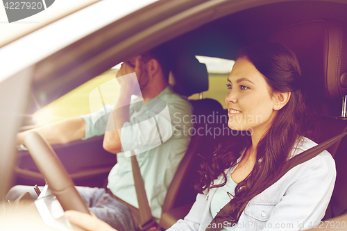 Image of woman driving car and man covering face with palm