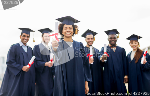 Image of happy students in mortar boards with diplomas