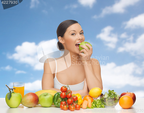 Image of woman with fruits and vegetables eating apple