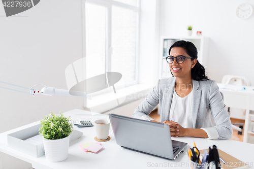 Image of happy smiling businesswoman with laptop at office