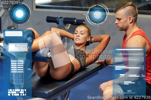 Image of woman with personal trainer doing sit ups in gym