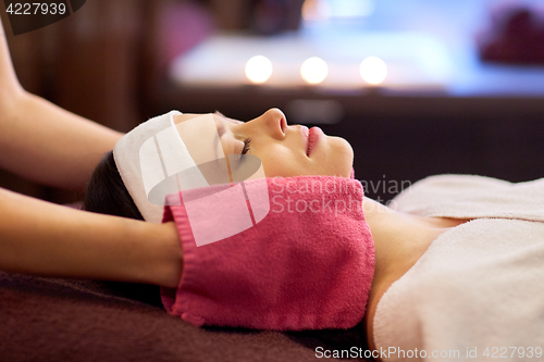 Image of woman having face massage with terry gloves at spa