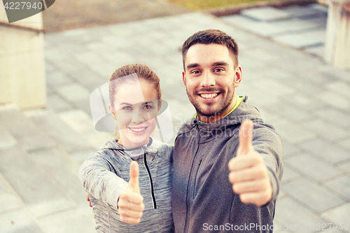 Image of smiling couple showing thumbs up on city street