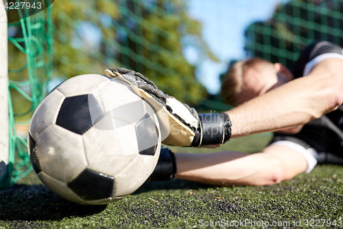 Image of goalkeeper with ball at football goal on field