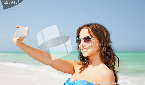 Image of woman in swimsuit taking selfie with smatphone