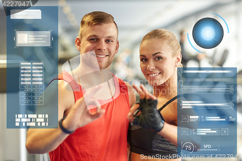 Image of smiling man and woman showing ok hand sign in gym