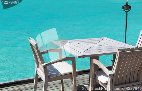 Image of table and chairs at restaurant terrace over sea