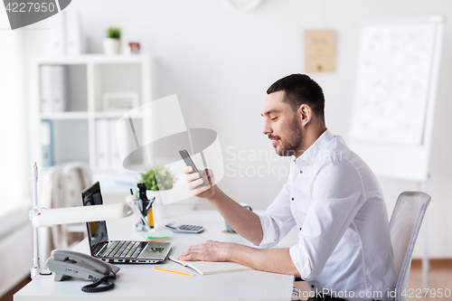 Image of businessman with smartphone and notebook at office