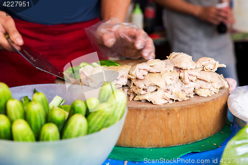 Image of cook with poultry and cucumbers at street market