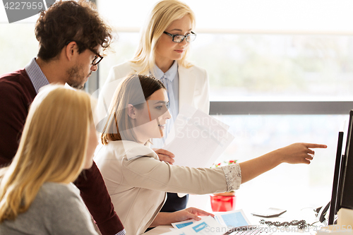 Image of happy creative team with computer in office