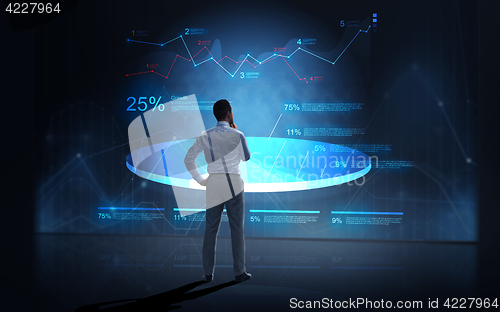 Image of businessman looking at virtual charts over dark