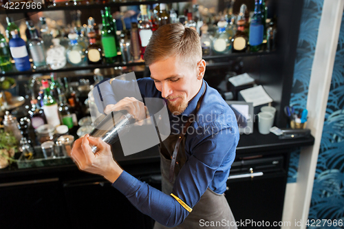 Image of happy barman with shaker preparing cocktail at bar