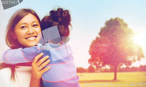 Image of happy mother and daughter hugging outdoors