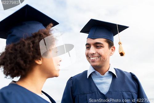 Image of happy students or bachelors in mortarboards