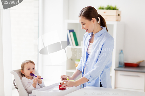 Image of mother and baby with spoon eating puree at home