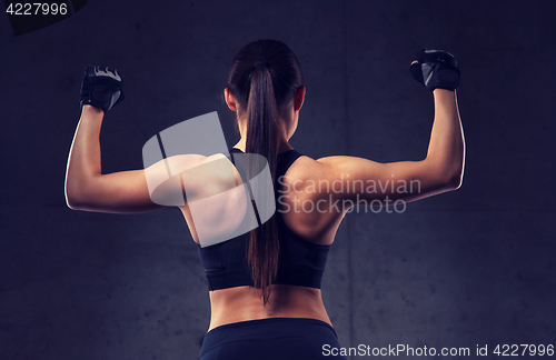 Image of young woman flexing muscles in gym