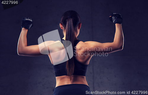 Image of young woman flexing muscles in gym