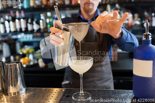 Image of barman with shaker preparing cocktail at bar