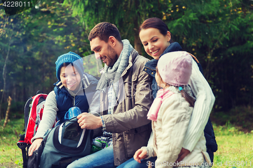 Image of happy family with backpacks and thermos at camp