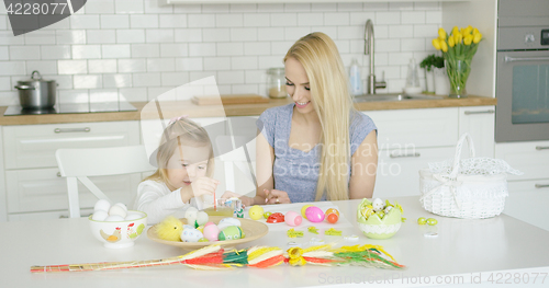 Image of Loving mother and daughter coloring eggs