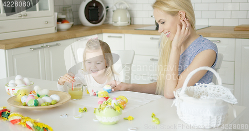 Image of Laughing woman and little girl coloring eggs