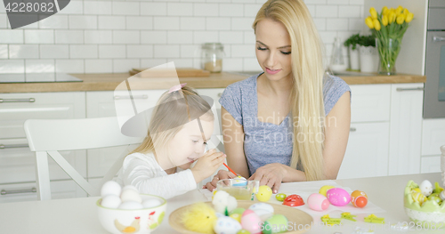 Image of Young female and little girl painting eggs