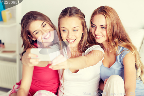 Image of teen girls with smartphone taking selfie at home