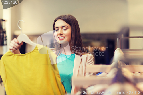 Image of happy young woman choosing clothes in mall