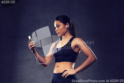 Image of woman with smartphone and earphones in gym