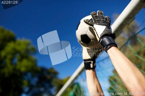 Image of goalkeeper with ball at football goal on field