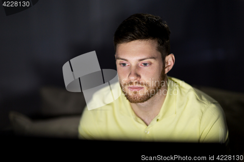 Image of young man watching tv at night