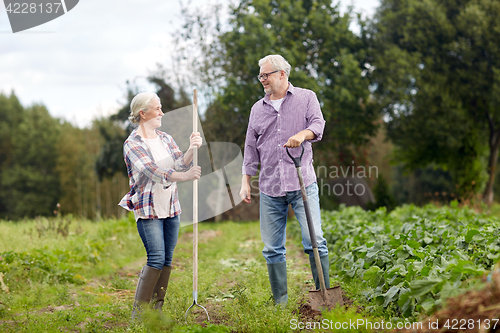 Image of senior couple with shovels at garden or farm