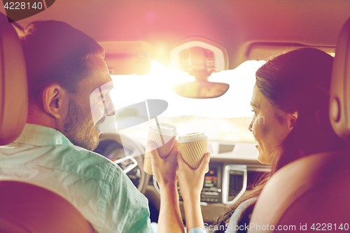 Image of happy man and woman driving in car with coffee