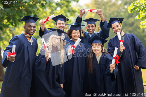 Image of happy students in mortar boards with diplomas