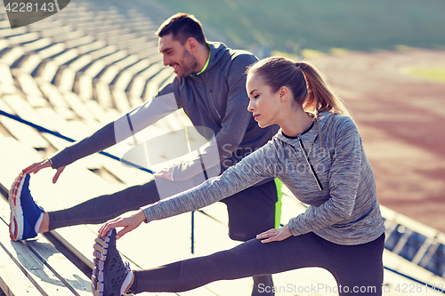 Image of couple stretching leg on stands of stadium