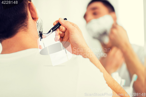 Image of close up of man shaving beard with razor blade