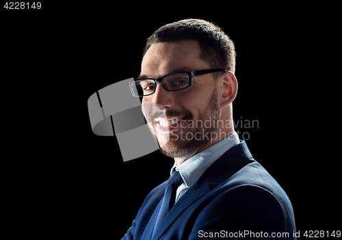 Image of smiling businessman in glasses over black