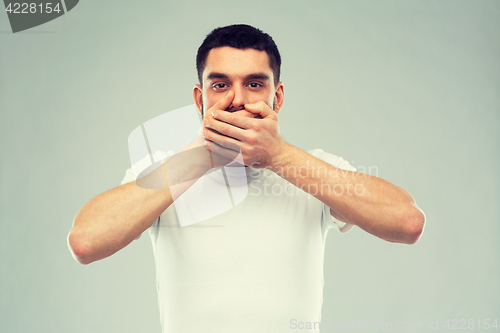 Image of man in white t-shirt covering his mouth with hands