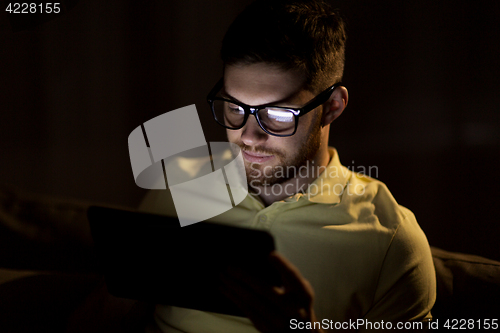 Image of young man with tablet pc networking at night