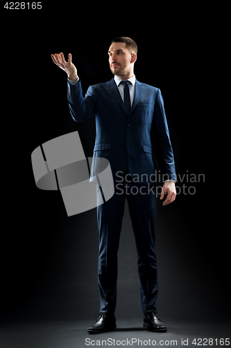 Image of businessman in suit holding something invisible