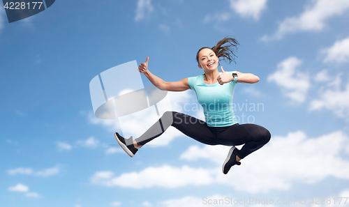 Image of happy sporty young woman jumping in blue sky