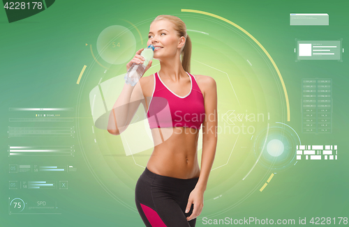 Image of happy sporty woman drinking water from bottle