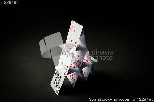 Image of house of playing cards over black background