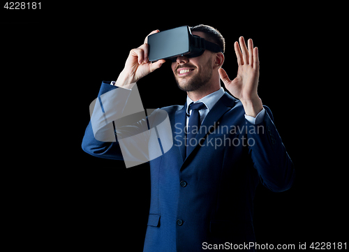 Image of businessman in virtual reality headset over black